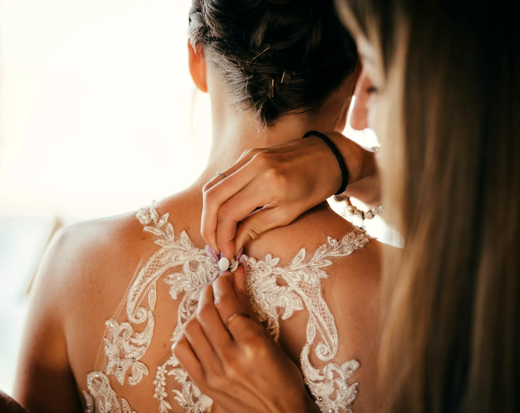 Une proche boutonne le dos en dentelle de la robe de la mariée