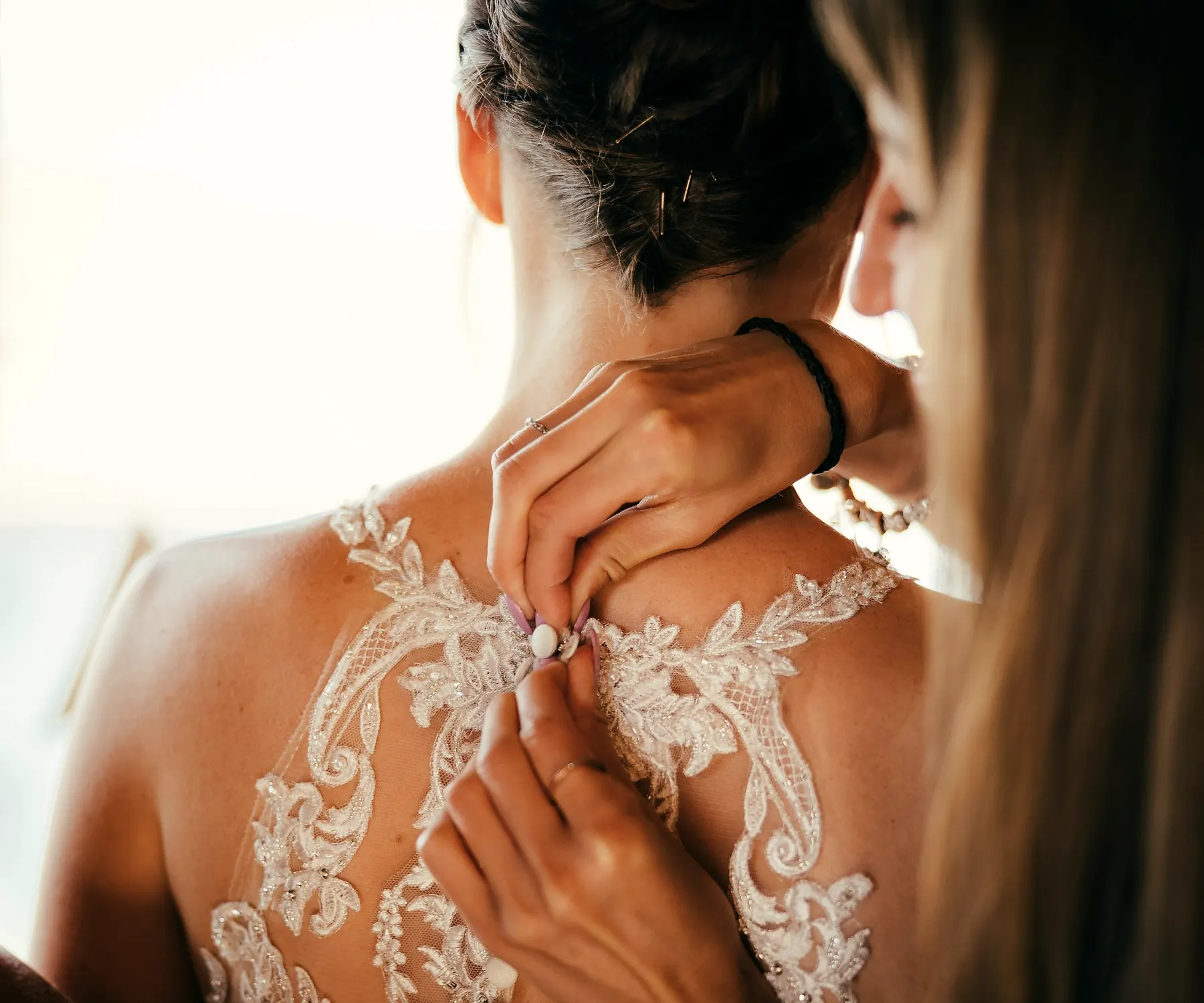 Une proche boutonne le dos en dentelle de la robe de la mariée